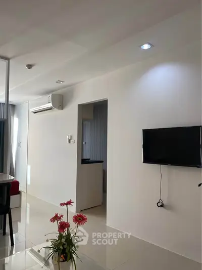 Modern living room with wall-mounted TV and air conditioning in a bright apartment.