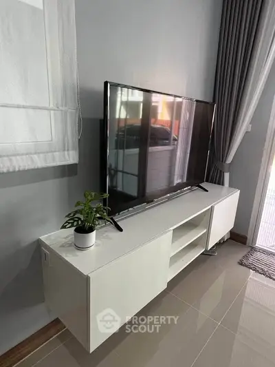 Modern living room with sleek TV stand and large flat-screen TV, perfect for entertainment.