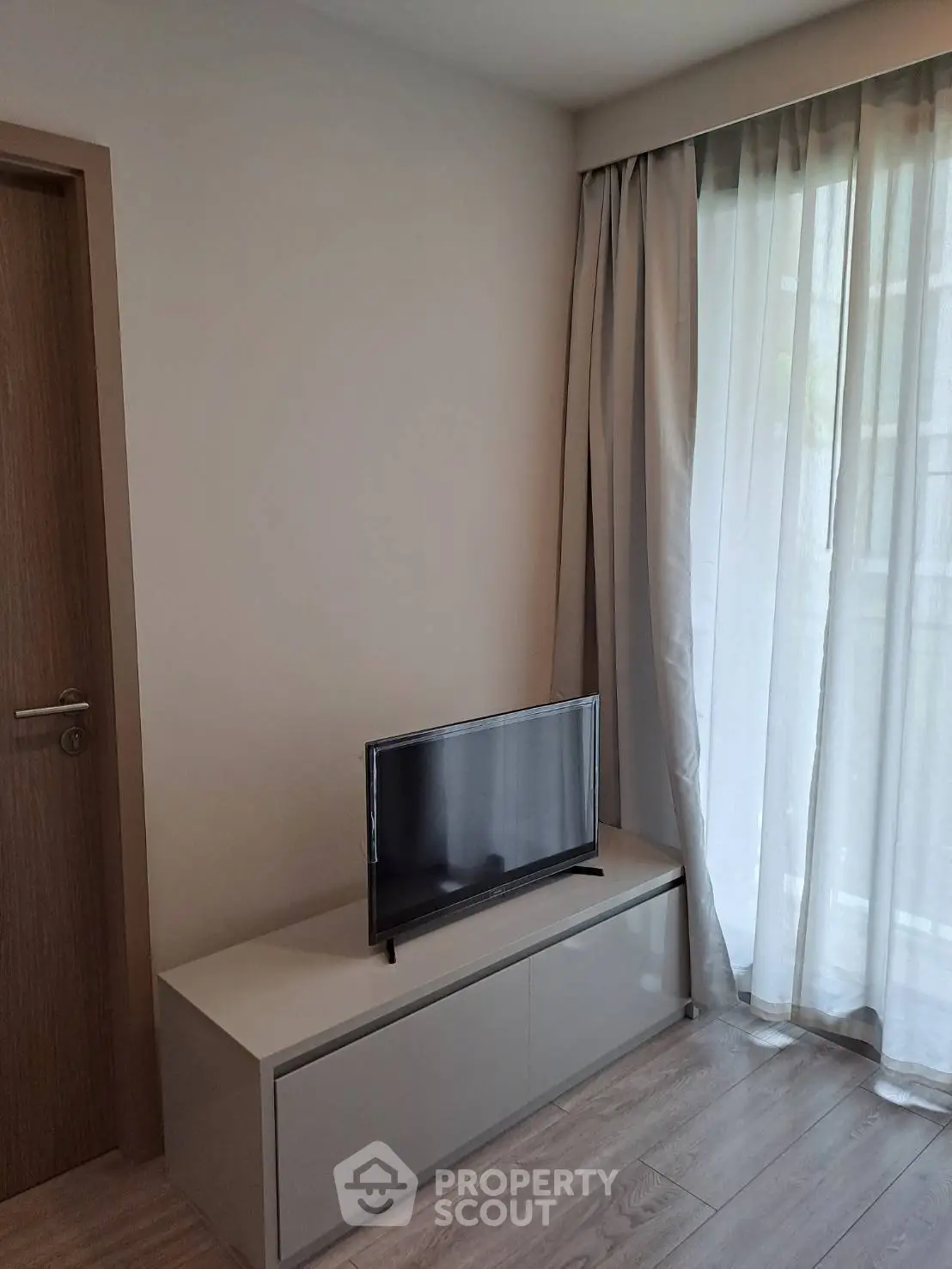 Modern living room with sleek TV stand and floor-to-ceiling curtains