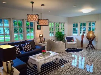 Charming living room with elegant decor and large windows offering lush garden views.