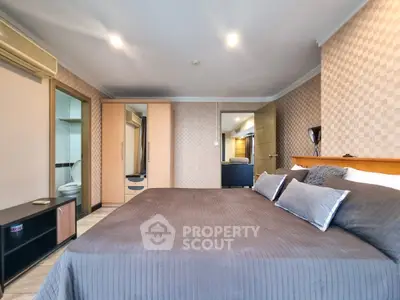 Spacious bedroom with modern decor and ensuite bathroom in luxury apartment.