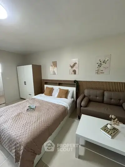 Cozy bedroom with stylish decor, featuring a comfortable bed, modern sofa, and elegant wall art.