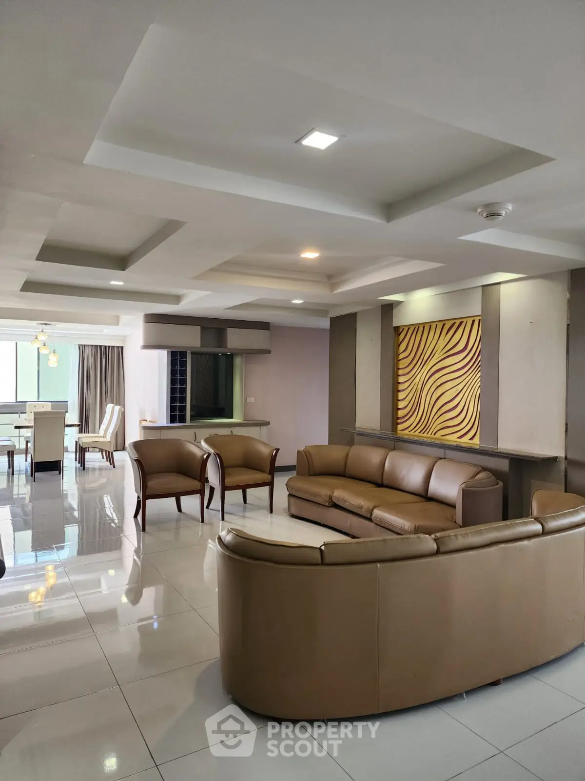 Spacious modern living room with elegant leather furniture and stylish ceiling design.