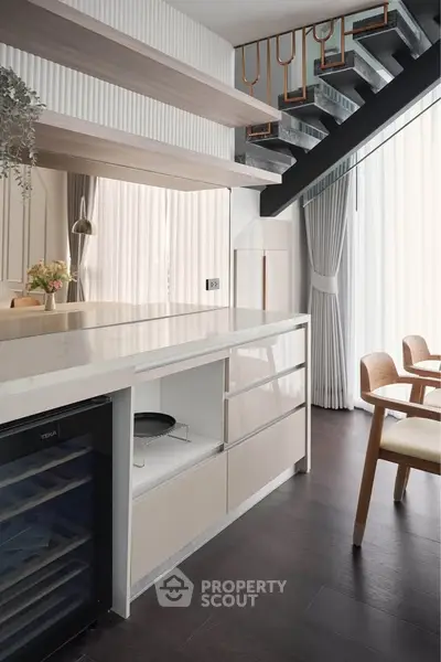 Modern kitchen with sleek design, open layout, and stylish staircase, perfect for contemporary living.