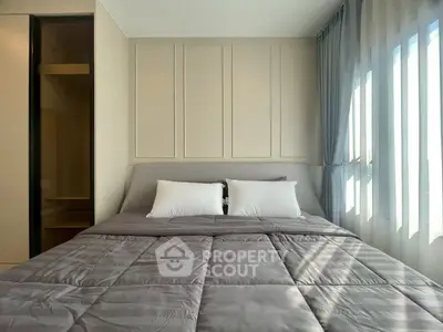 Modern bedroom with cozy bedding and large window offering natural light