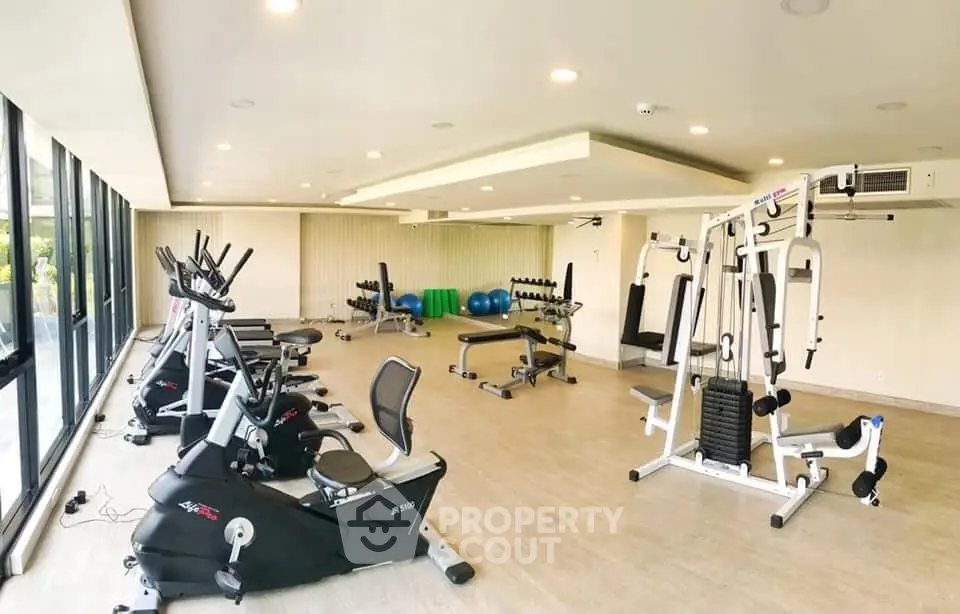 Spacious modern gym with state-of-the-art fitness equipment and large windows for natural light.