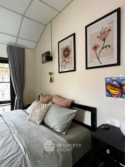 Cozy bedroom with stylish decor and framed art, featuring a comfortable bed and soft lighting.