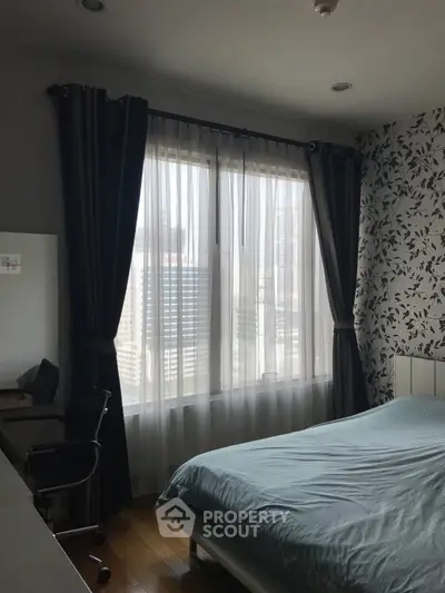Cozy bedroom with large window and city view, featuring modern decor and natural light.