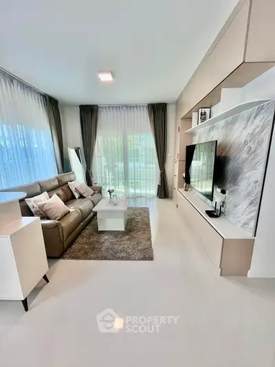 Modern living room with sleek design, large TV, and natural light from floor-to-ceiling windows.