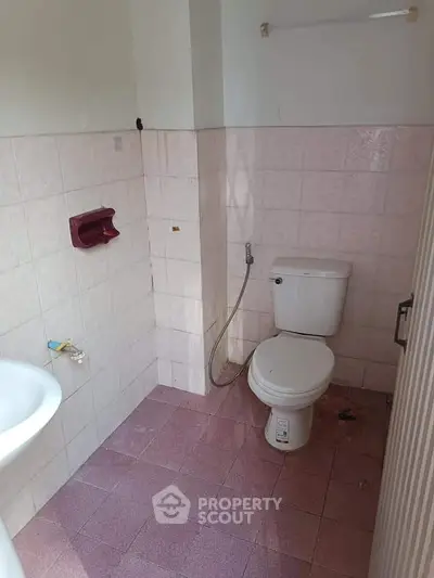 Compact bathroom with tiled walls and floor, featuring a toilet and sink.