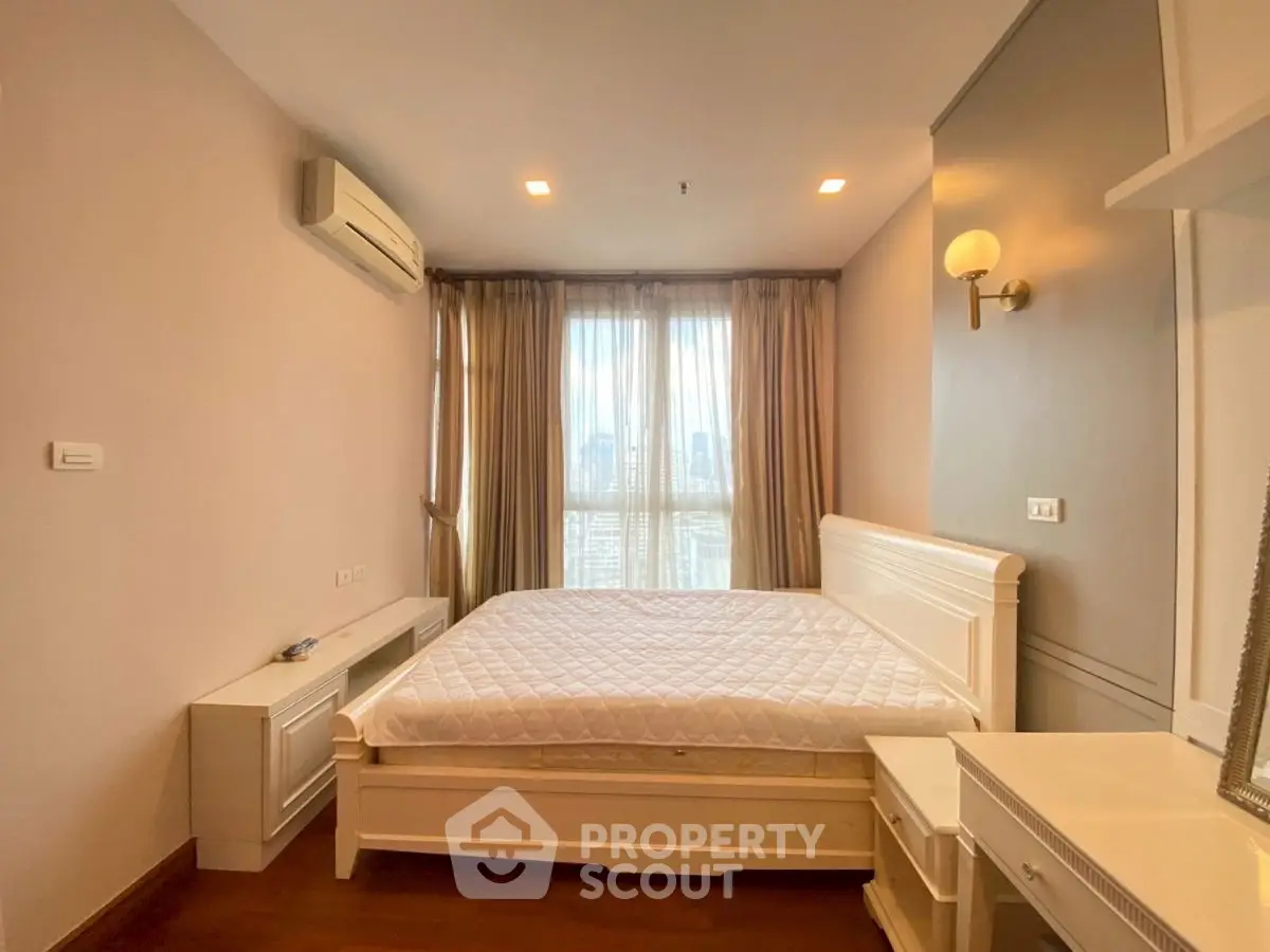 Spacious bedroom with city view, elegant furnishings, and ample natural light.