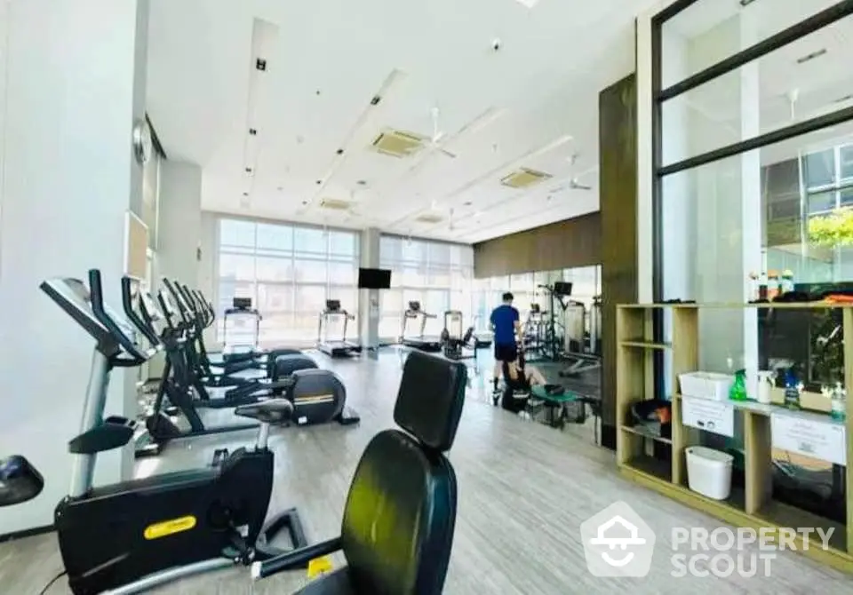 Spacious modern gym with state-of-the-art equipment and large windows for natural light.