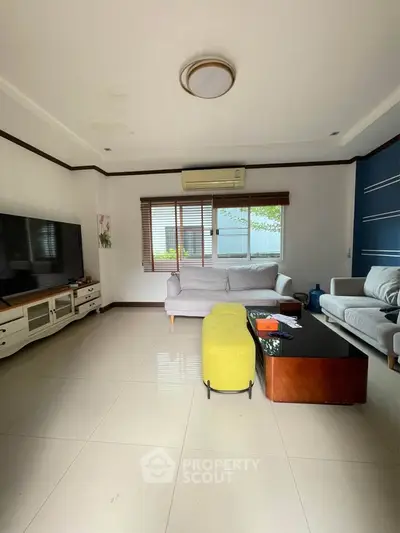 Spacious living room with modern furniture and large window for natural light.