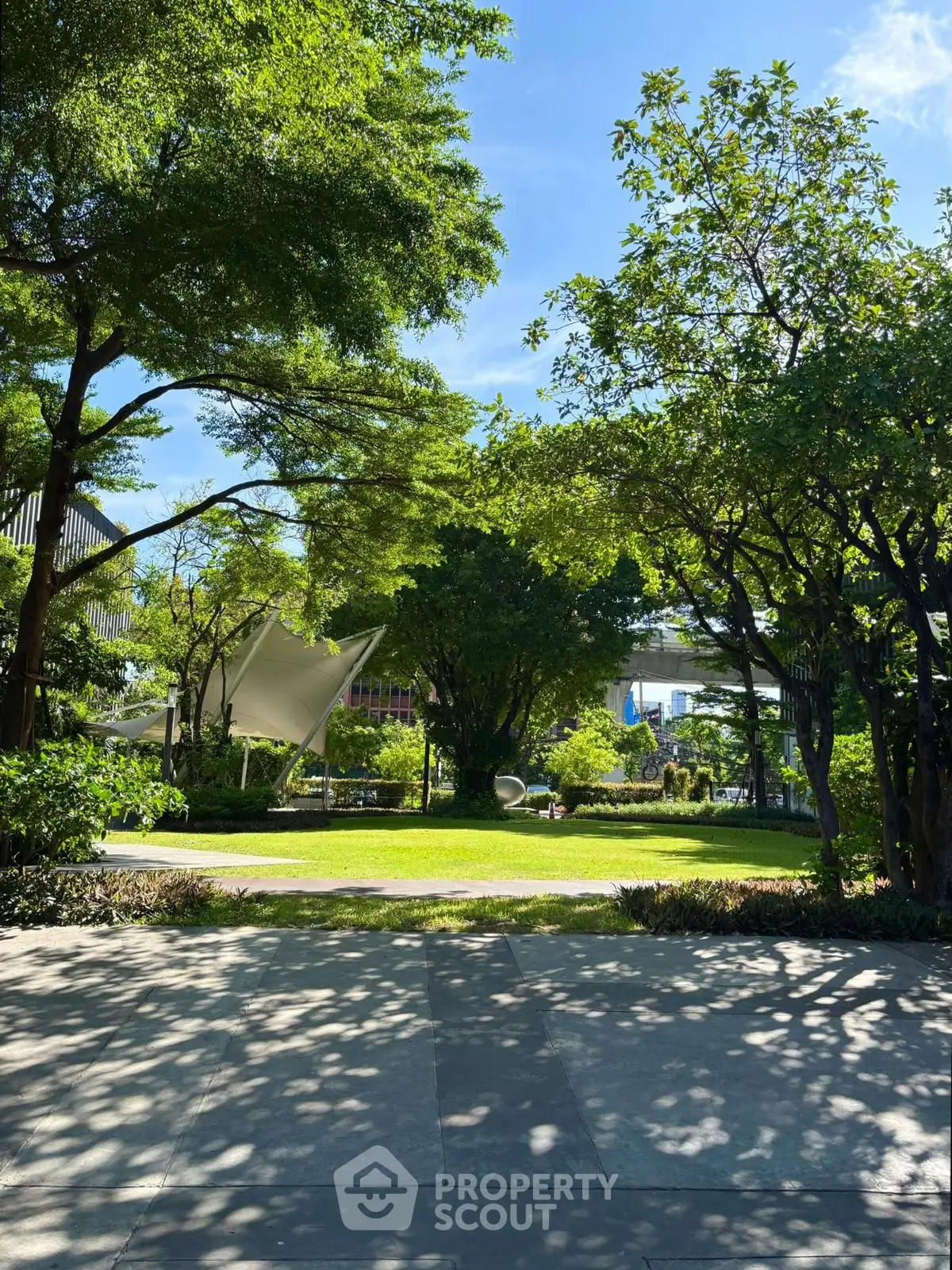 Lush green garden with trees and open space in a modern residential complex.