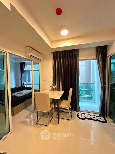 Modern apartment interior with dining area and bedroom view, featuring sleek design and natural light.