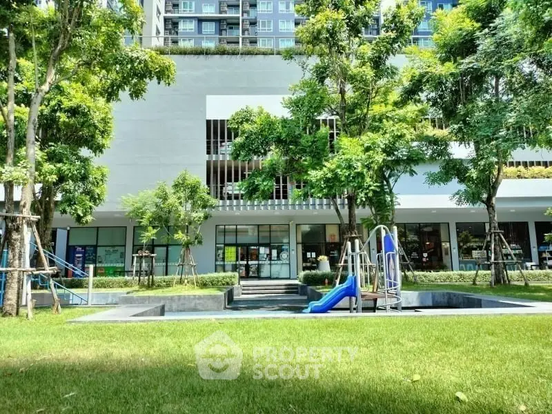 Modern apartment building with lush garden and children's playground.