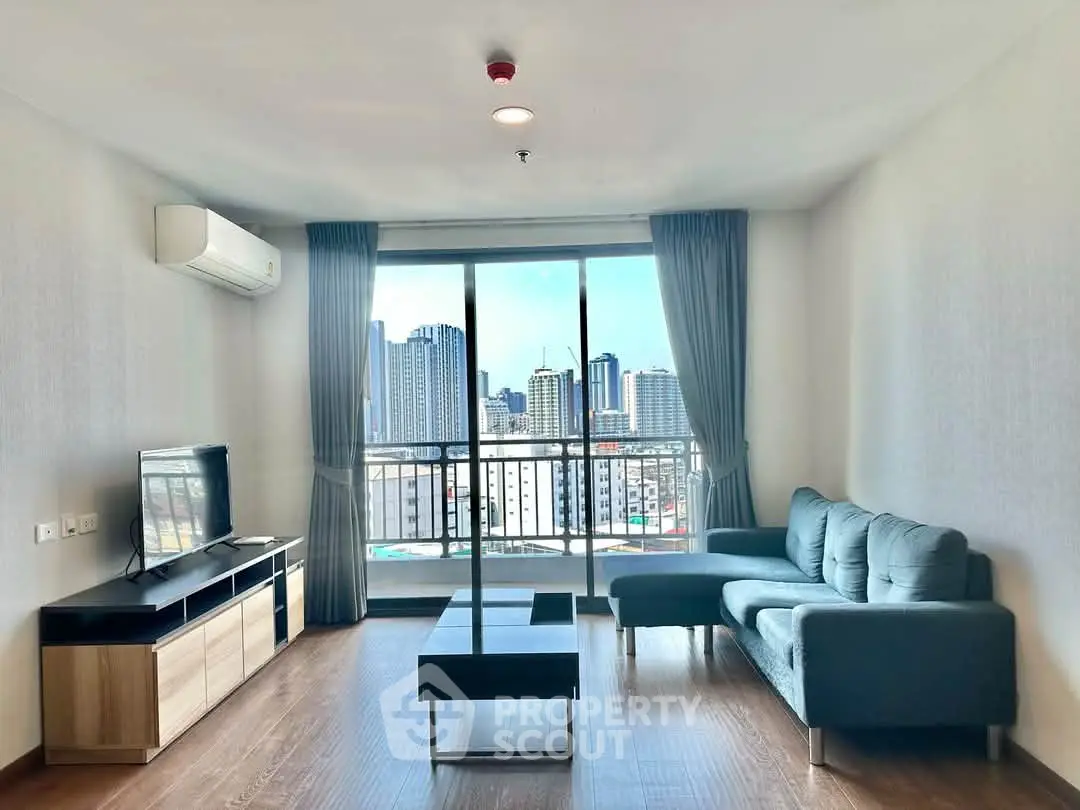 Spacious living room with city view, modern furniture, and large windows in a high-rise apartment.