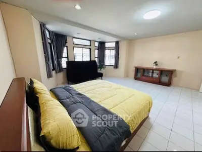 Spacious bedroom with large windows and modern furnishings in a well-lit apartment.