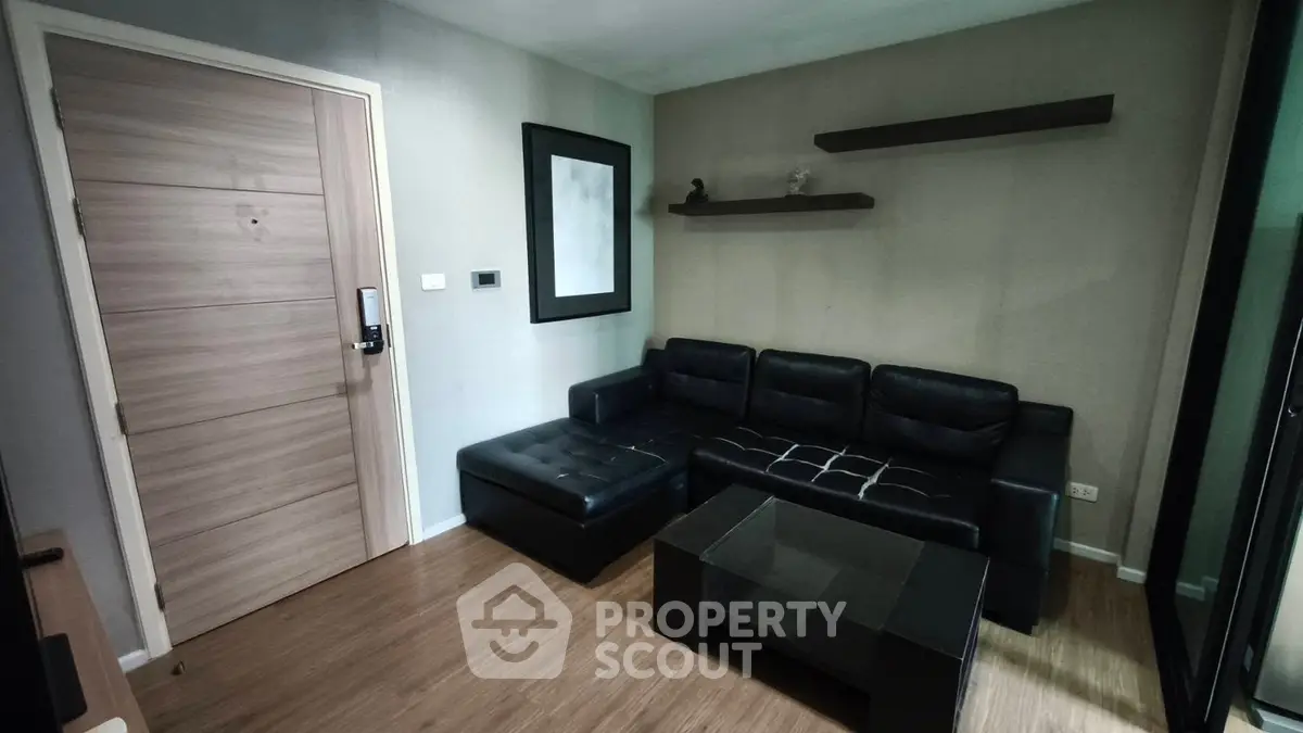 Modern living room with black leather sofa and wooden flooring