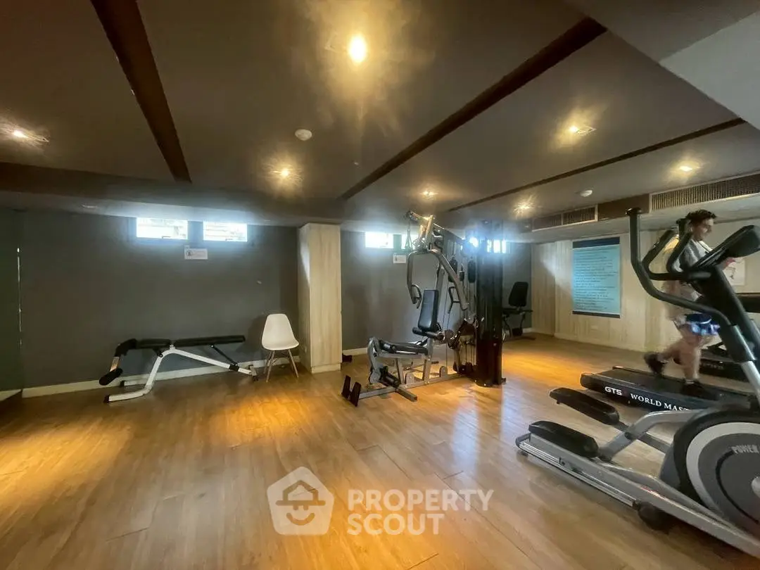 Spacious gym with modern equipment and wooden flooring in a residential building.