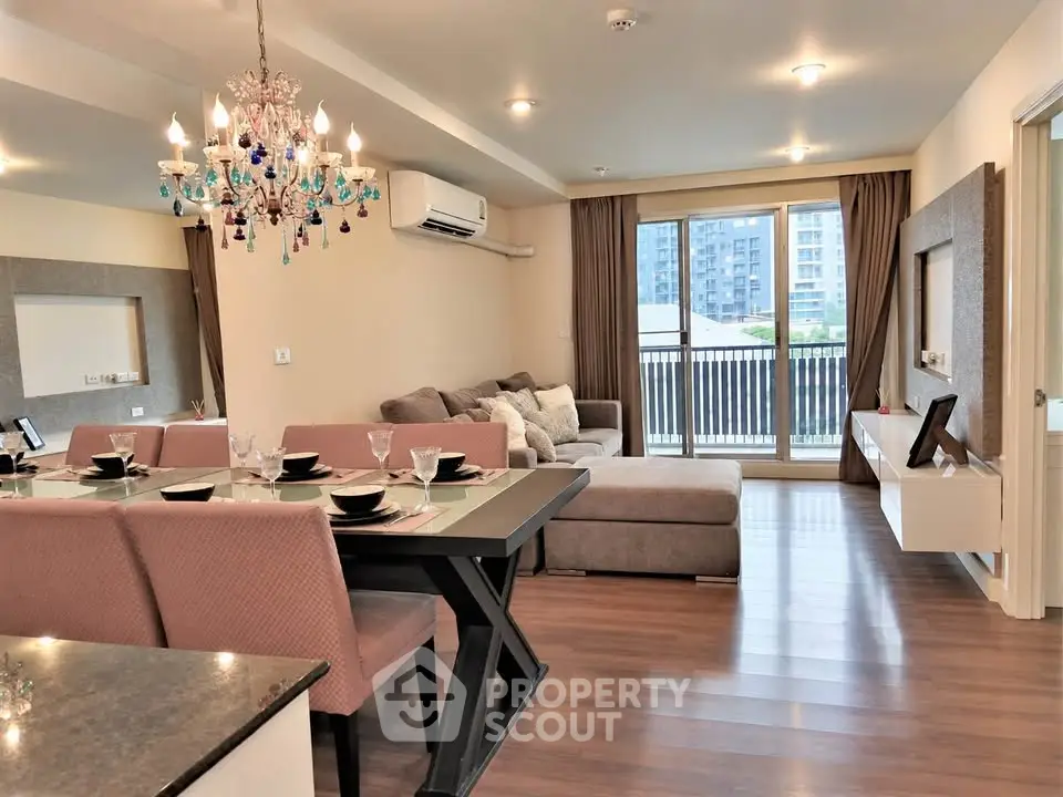 Elegant living room with chandelier, modern furniture, and large windows offering city views.