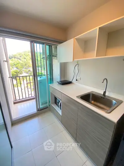 Modern kitchen with balcony view, featuring sleek cabinetry and built-in appliances.