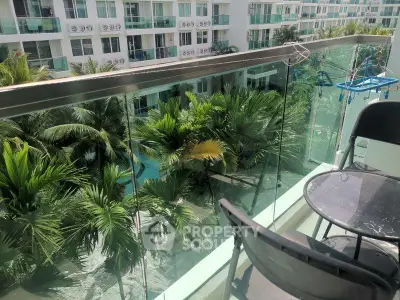 Charming balcony view overlooking lush greenery and modern apartment complex, perfect for relaxation.
