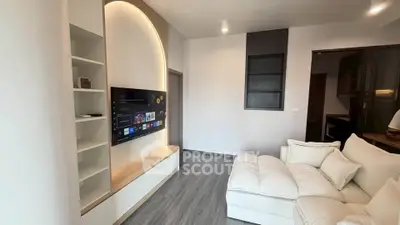 Modern living room with sleek design and wall-mounted TV, featuring cozy white sofa and stylish shelving.