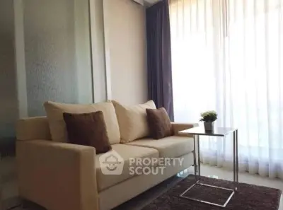 Cozy living room with elegant sofa and natural light through sheer curtains.