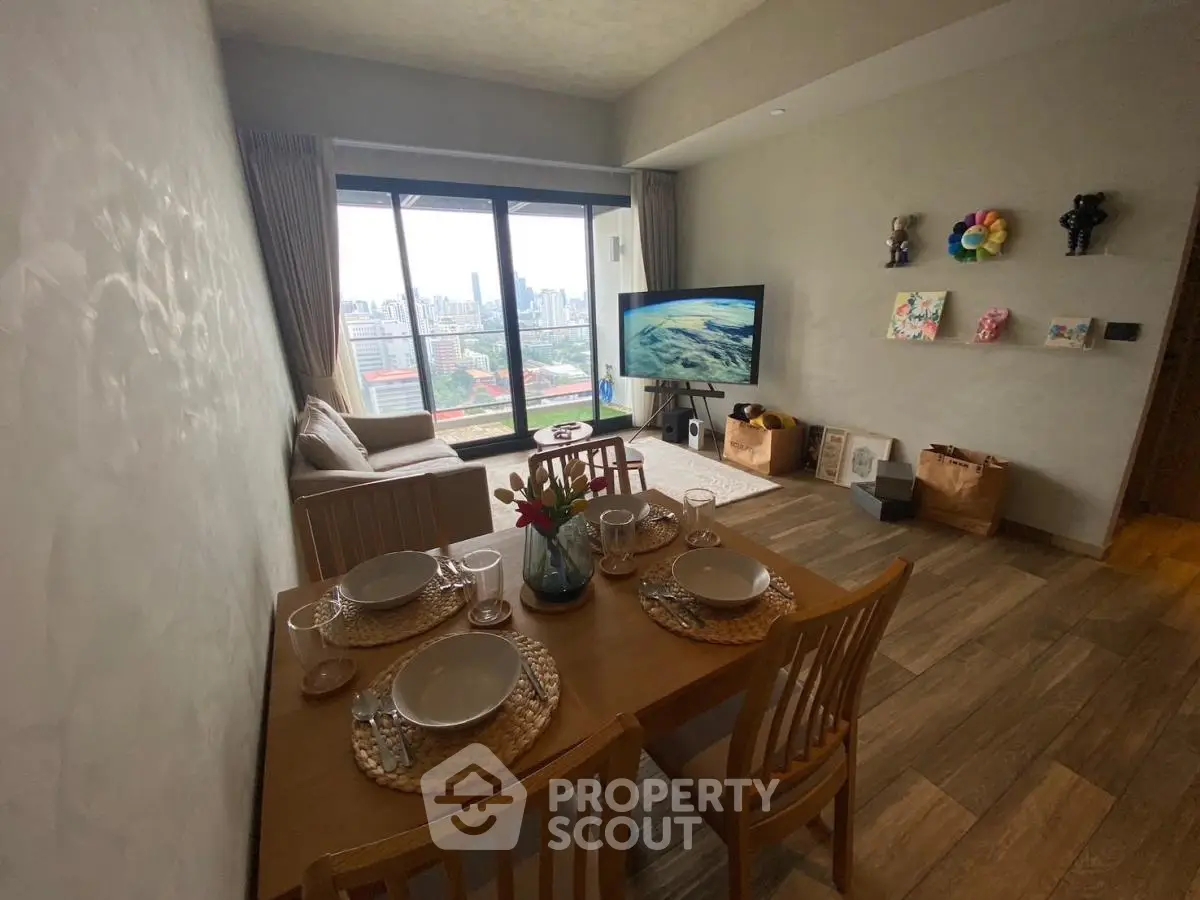 Modern living room with city view, stylish decor, and dining area in a high-rise apartment.
