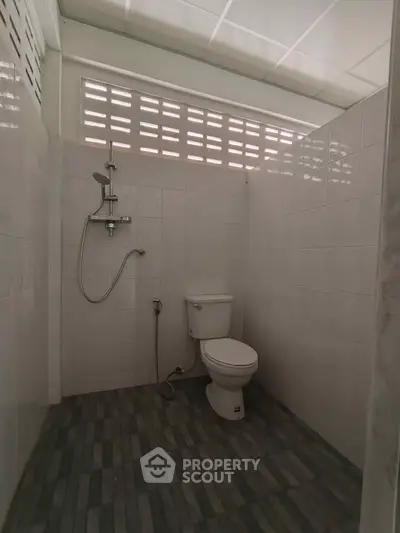 Compact bathroom with shower and toilet, featuring tiled walls and floor.