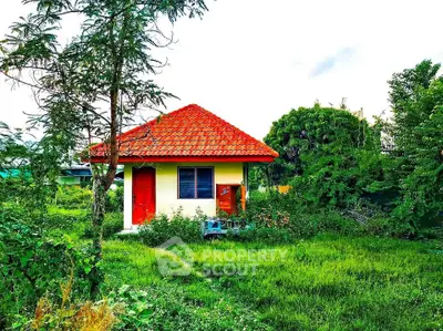 Charming small house with red roof nestled in lush green surroundings, perfect for serene living.