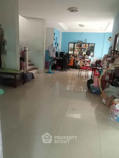 Spacious living area with tiled flooring and modern decor, featuring a home office setup and ample natural light.
