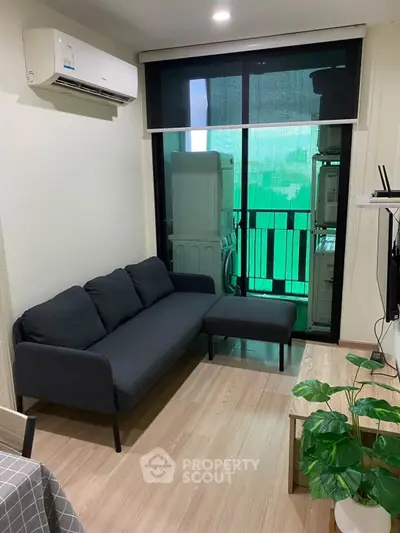 Modern living room with sleek black sofa, air conditioning, and balcony view in stylish apartment.