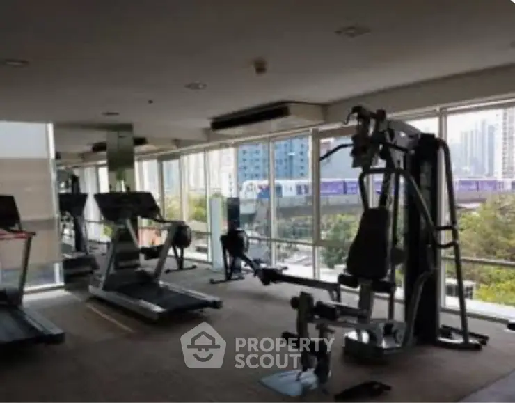 Modern gym with city view and fitness equipment in luxury apartment building.