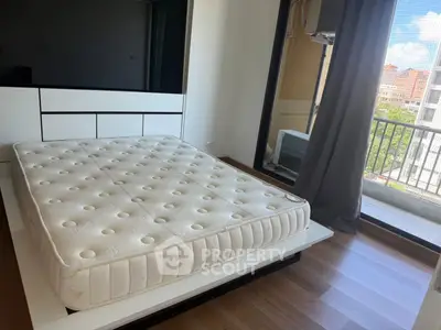 Spacious bedroom with modern design and balcony view, featuring a comfortable mattress and sleek flooring.