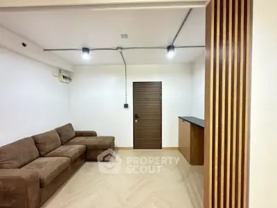 Modern living room with brown sofa and wooden accents, featuring minimalist design and cozy ambiance.