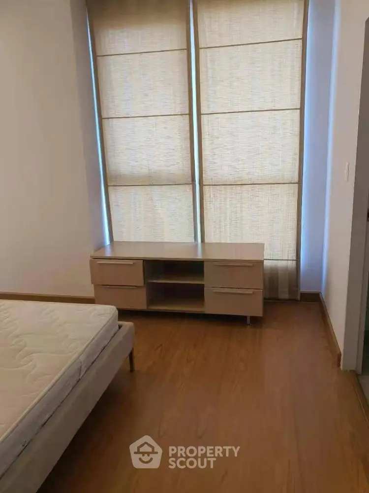 Spacious bedroom with wooden flooring and modern furniture