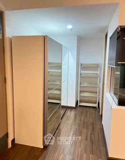 Spacious storage area with modern shelving and wooden flooring in a contemporary apartment.