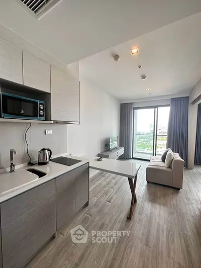 Modern open-plan living room with sleek kitchen and balcony view