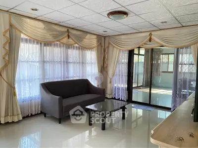 Elegant living room with large windows and stylish curtains, featuring a modern sofa and glass coffee table.