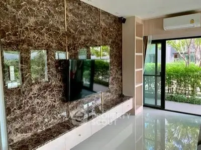 Luxurious living room with marble accent wall and large TV, overlooking a lush garden view.