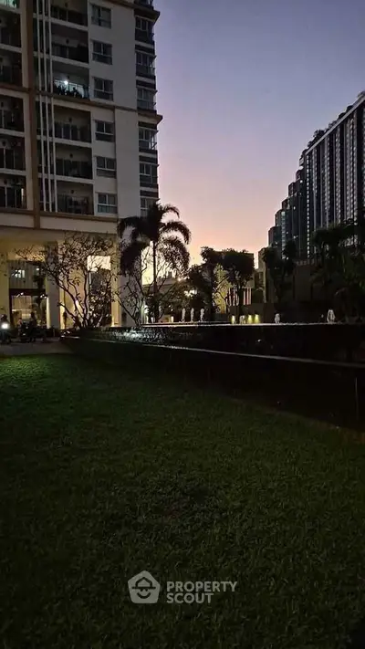 Stunning evening view of modern apartment complex with lush garden and elegant water features.