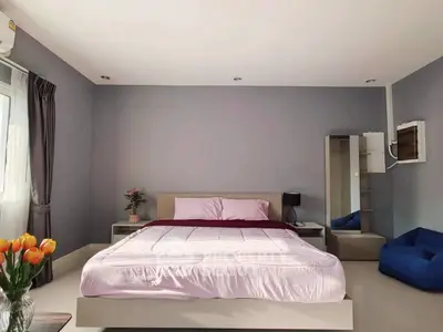 Spacious bedroom with modern decor and natural light, featuring a cozy bed and stylish furnishings.