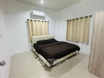 Modern bedroom with minimalist design and air conditioning, featuring a comfortable bed and neutral decor.