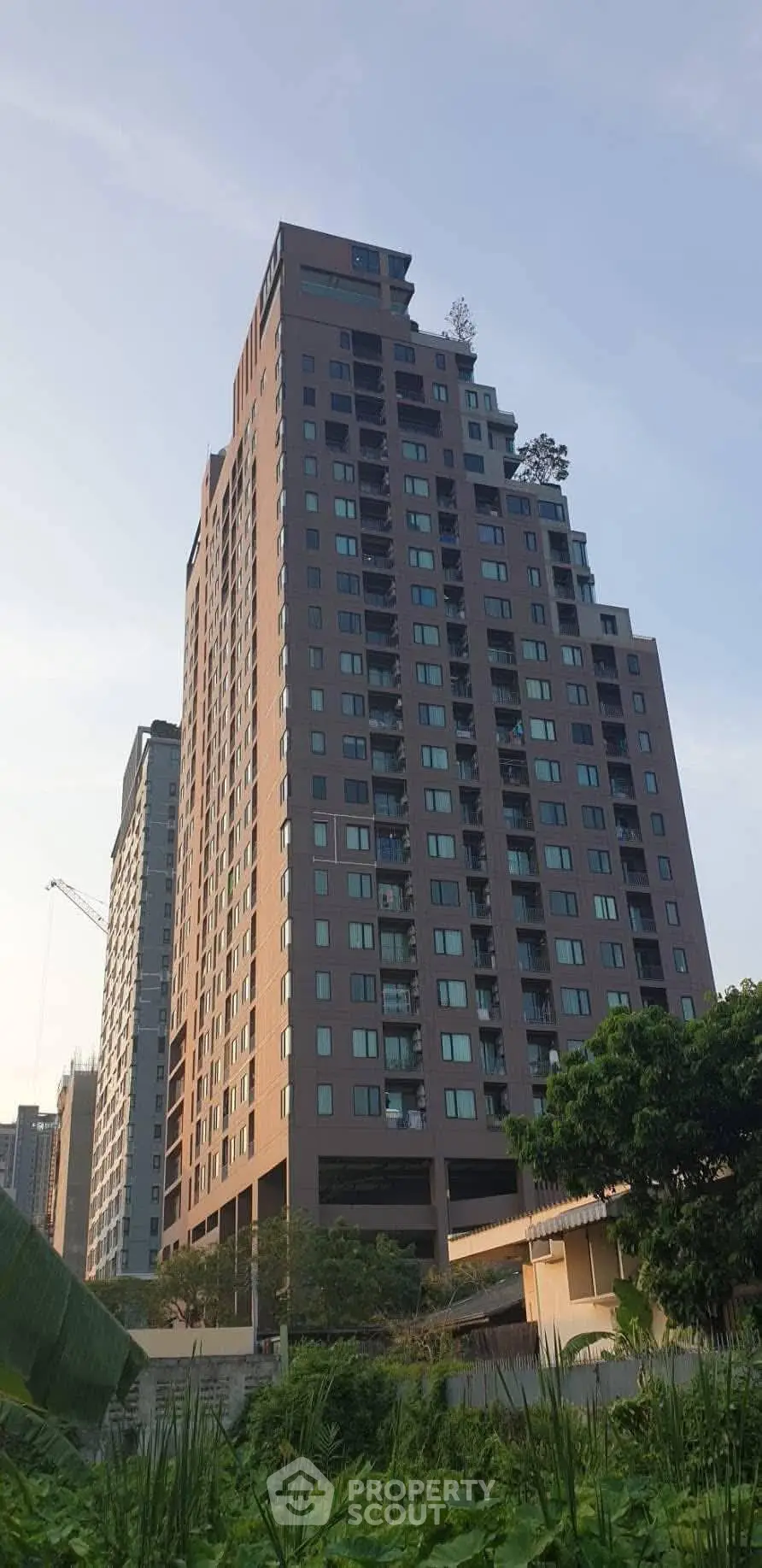Modern high-rise apartment building with lush greenery in urban setting