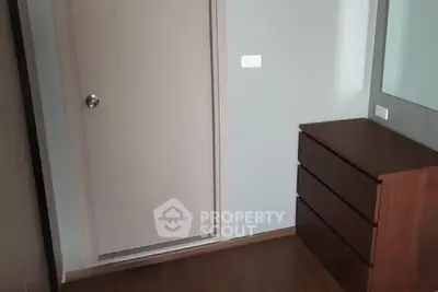 Minimalist bedroom corner with wooden dresser and modern door