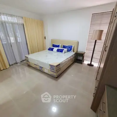 Spacious bedroom with natural light and modern furnishings in a stylish apartment.