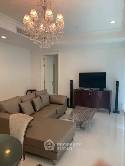 Elegant living room with modern sofa, chandelier, and flat-screen TV, perfect for relaxation and entertainment.