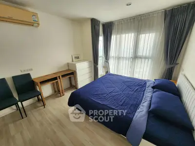 Spacious bedroom with modern decor and large windows offering natural light.